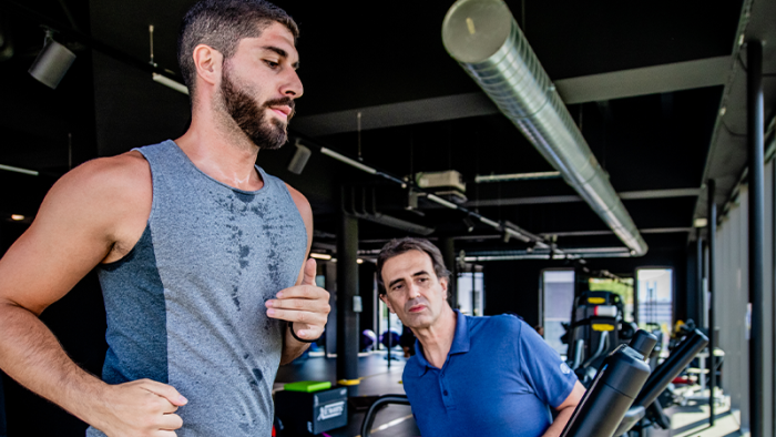 Un uomo atletico corre su un tapis roulant sotto l'osservazione di un fisioterapista sportivo presso lo Swiss Medical Network